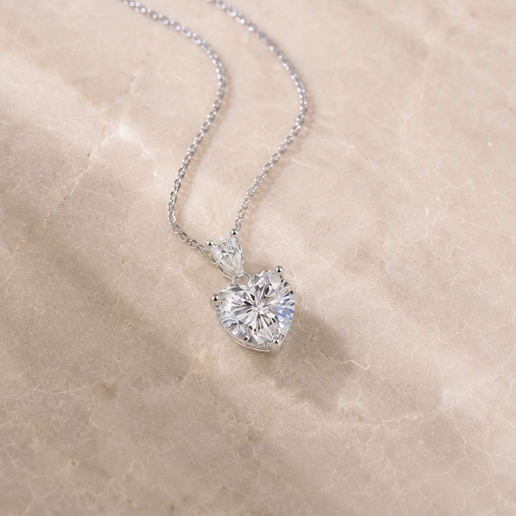 Heart shaped moissanite pendant necklace on a neutral stone background