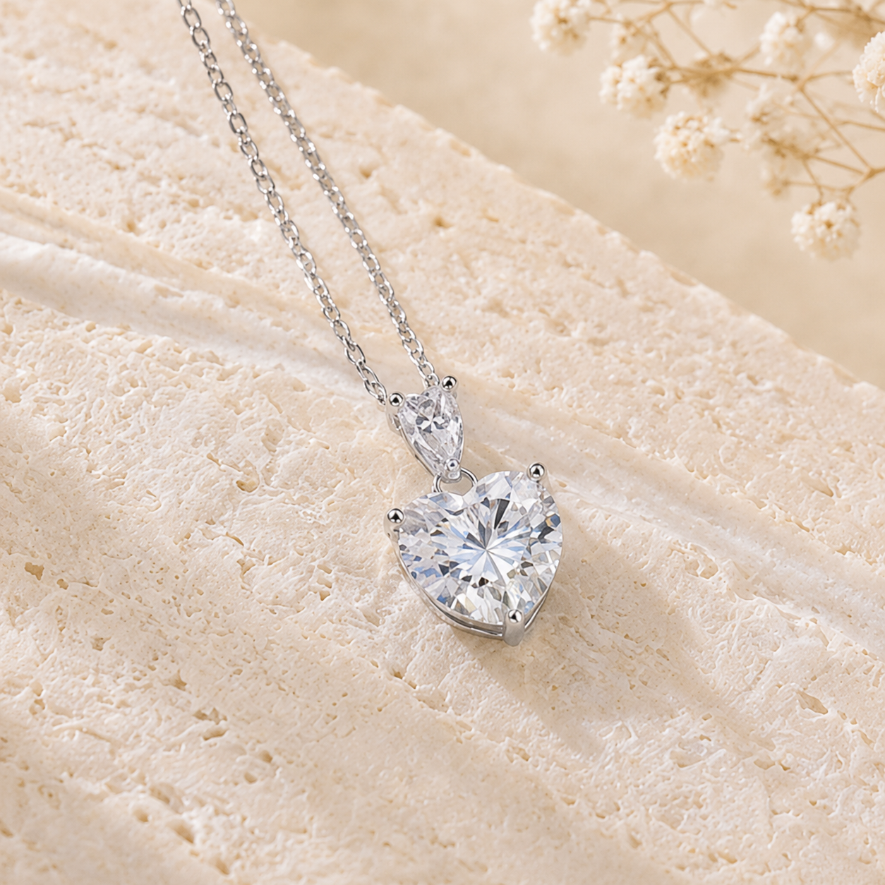 Heart cut moissanite necklace styled on a textured ivory background